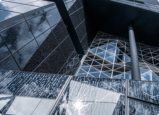 Larchitecture met en scène un bâtiment moderne avec des surfaces vitrées réfléchissantes et des motifs géométriques, créant un jeu complexe de lumière et de reflets. Une haute colonne noire soutient un surplomb, tandis que les nuages dansent sur la façade en verre miroir.